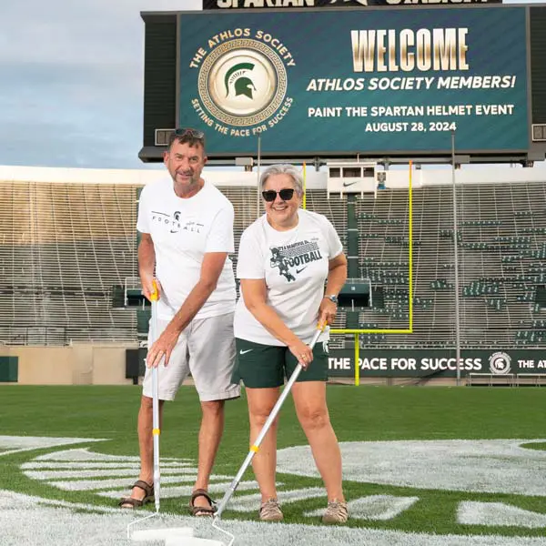two volunteers helping paint the field