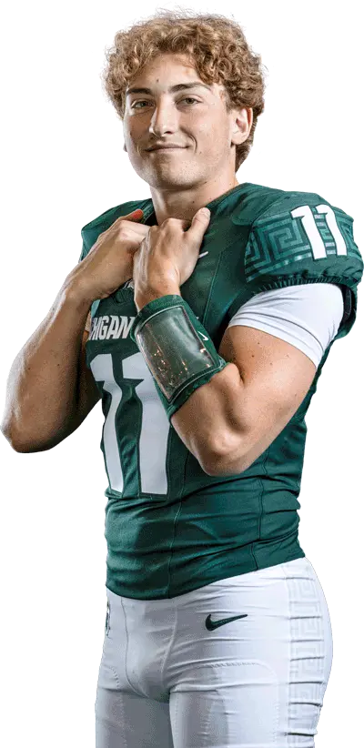 Football player posing in uniform with a football