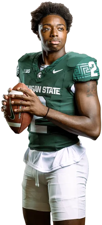 Football player posing in uniform with a football