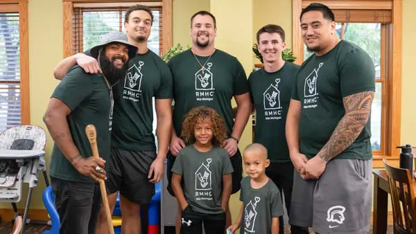 student-athletes posing with young children